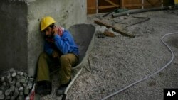 FILE - A construction worker takes time off to call a friend in Doha, Qatar, Nov. 30, 2006. Like other energy-rich Gulf nations, Qatar relies heavily on migrant workers drawn mainly from South Asia to build its roads, skyscrapers and stadiums.