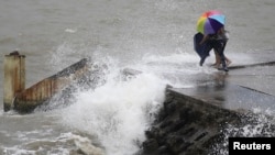 People move away as waves caused by Typhoon Utor crash on a seawall in Haikou, Hainan province, China, Aug. 14, 2013.