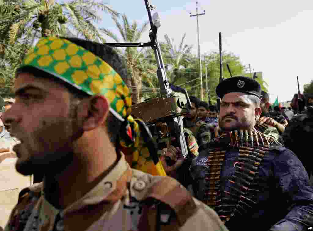 Shi'ite tribal fighters raise their weapons and chant slogans against the Islamic State of Iraq and the Levant in Basra, Iraq, June 16, 2014. 