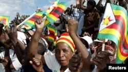 FILE: Zimbabwe political supporters wave flags in Gutu, a rural town 220 Km's south-east of the capital [Harare].