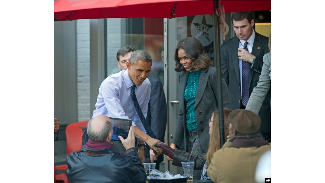 President Barack Obama, accompanied by first lady Michelle Obama, greets patrons after they had lunch with members of the Standing Rock Sioux Tribal Youth at We the Pizza/Good Stuff Eatery restaurant in the Capitol Hill neighborhood of Washington, DC, Nov. 20, 2014.