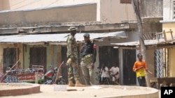 FILE - Security forces stand guard at the site of bomb explosion at a market in Maiduguri, Nigeria, March 7, 2015. On Friday, dozens of people were killed when two female suicide bombers attacked a market in the town of Madagali.