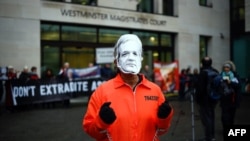 Seorang pemrotes mengenakan topeng bergambar wajah pendiri Wikileaks, Julian Assange dengan pakaian penjaranya, di depan pengadilan Westminster, London, 19 Desember 2019. 