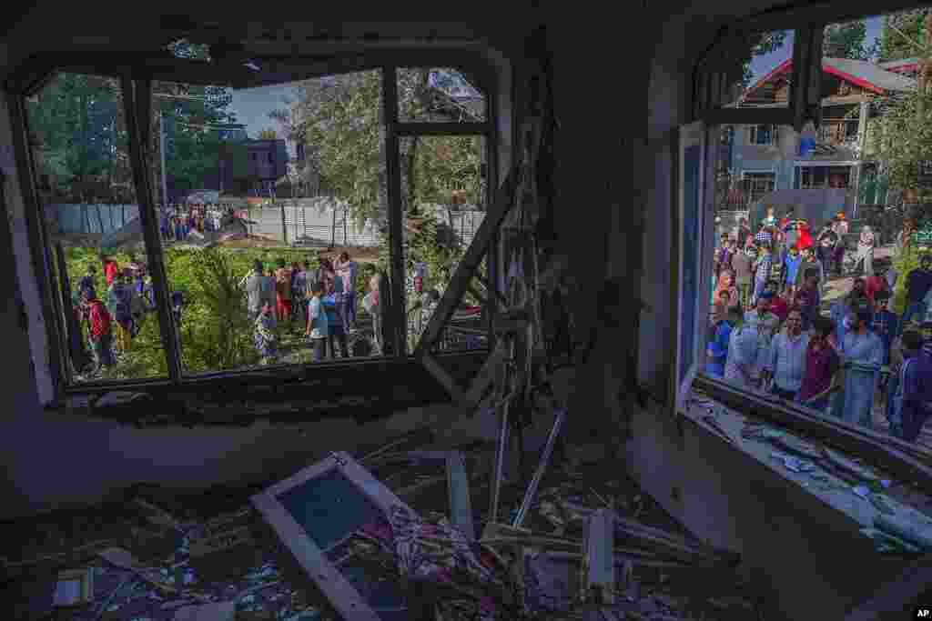 Kashmiris gather outside a house damaged in a gunbattle in the outskirts of Srinagar, Indian controlled Kashmir.