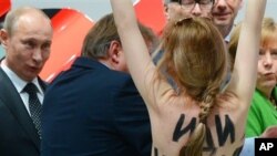 Một người biểu tình ngực trần viết những lời chống Tổng thống Nga trên lưng tiến về hướng Tổng thống Putin (trái) và Thủ tướng Merkel, 8/4/13