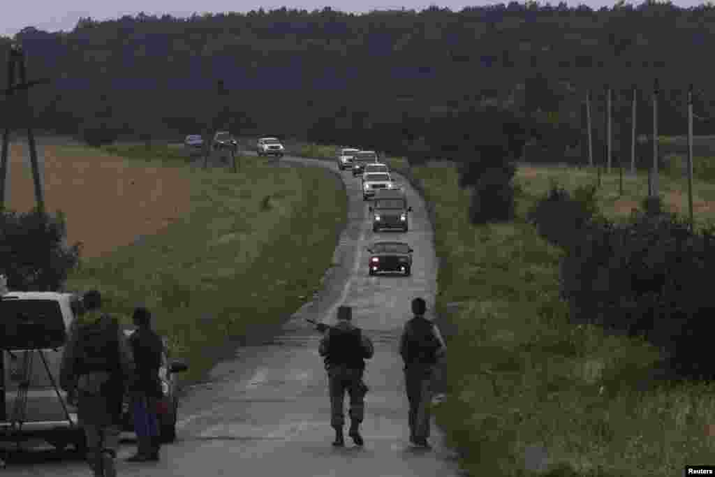 Pro-Russian separatists watch as Organization for Security and Cooperation in Europe (OSCE) monitors arrive at the crash site of Malaysia Airlines flight MH17, near the settlement of Grabovo in the Donetsk region, July 18, 2014. 