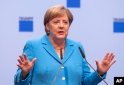 FILE - German chancellor Angela Merkel gestures during a discussion with TRUMPF employees in Neukirch, eastern Germany, Aug. 16, 2018.