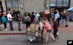 Shoppers pass a line of voters at a grocery store which is also serving as a polling site for the Texas primary elections, in Austin, Texas, March 6, 2018.
