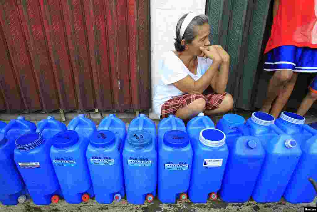 A resident queues with plastic containers to collect drinking water in Rosario, July 18, 2014.