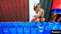 FILE - A resident queues with plastic containers to collect drinking water in Rosario.