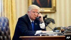 FILE - President Donald Trump speaks on the phone in the Oval Office of the White House in Washington, Jan. 28, 2017.