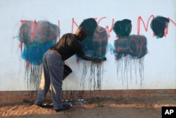FILE - A caretaker of a building attempts to rub off anti-government graffiti in Harare, Zimbabwe, Sept. 6, 2016. Protests have rocked Zimbabwe since July, calling on President Robert Mugabe to fix the economy and respect human rights.