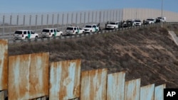 FILE - U.S. Border Patrol vehicles are parked along a secondary fence, seen from across the wall in Tijuana, Mexico, Dec. 9, 2018.