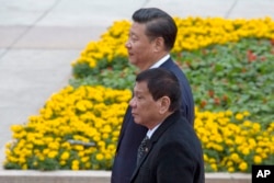 FILE - Philippine President Rodrigo Duterte, front, walks with Chinese President Xi Jinping during a welcome ceremony outside the Great Hall of the People in Beijing, China, Oct. 20, 2016.