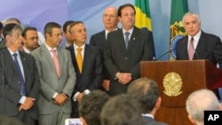 Brazil's President Michel Temer, right, reads a statement accompanied by supporters and ministers of his government, at the Planalto Presidential Palace, in Brasilia, June 27, 2017. 