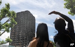 People look at the burned Grenfell Tower apartment building in London, June 23, 2017. Investigators have traced the source of the June 14 fire to a refrigerator in one of the fourth-floor apartments.