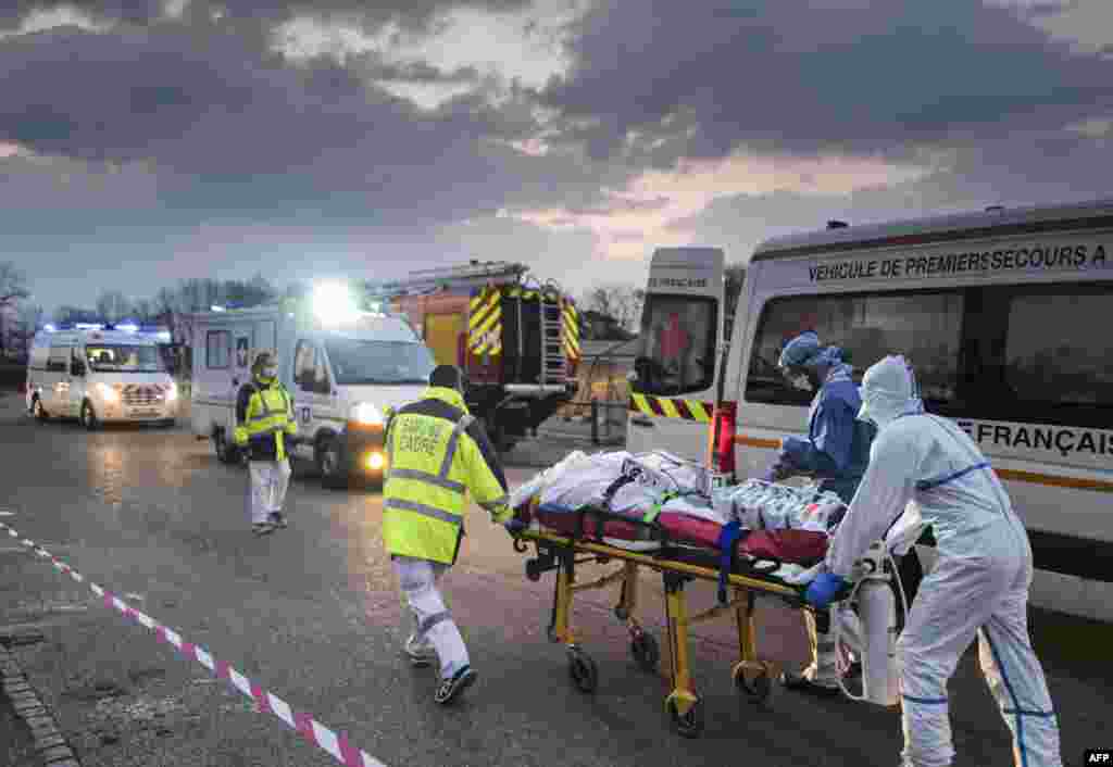 Emergency medical personnel carries a patient affected with coronavirus from a military hospital to an ambulance in Mulhouse, eastern France.