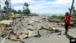 Seorang pria memeriksa jalan yang rusak setelah diterjang banjir di Dili, Timor Leste, Selasa 6 April 2021. Sejumlah bencana akibat cuaca buruk di kawasan timur Indonesia dan negara tetangga Timor Leste menyebabkan sejumlah orang tewas atau hilang. (Foto AP / Kandhi Barnez)