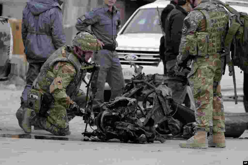 U.S. forces examine the remains of a car after a suicide car bomb attack on the Jalalabad-Kabul road in Kabul, Afghanistan, Dec. 27, 2013. 