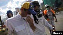 El líder opositor Henrique Capriles, centro, es auxiliado luego de ser afectado por el gas lacrimógeno y los golpes durante una protesta contra el gobierno en Caracas, el lunes 29 de mayo.