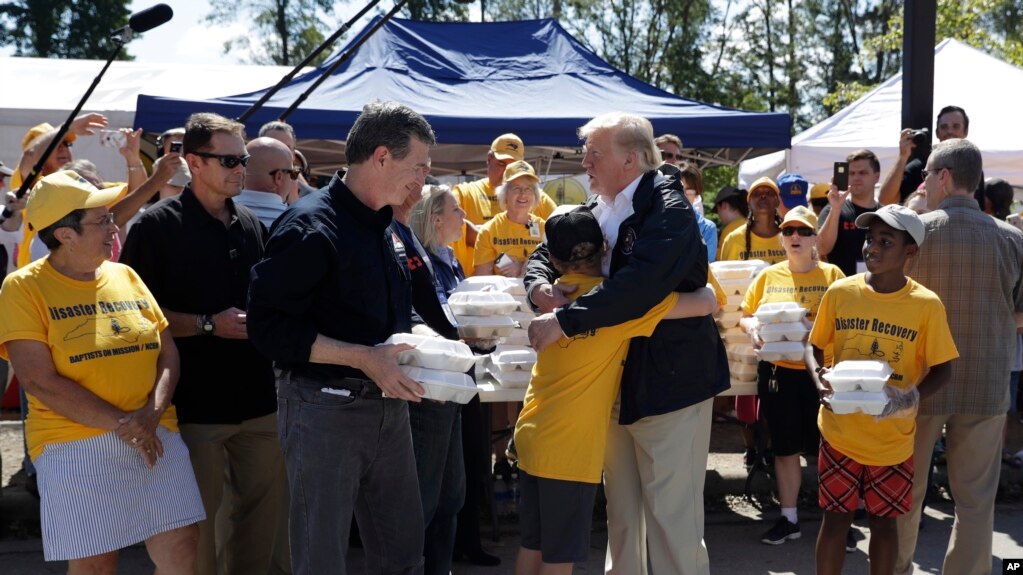 El presidente Donald Trump y el gobernador de Carolina del Norte, Roy Cooper, saludan a voluntarios mientras se preparan para entregar alimentos y otros insumos a personas afectadas por el huracán Florence, en New Bern, Carolina del Norte. 