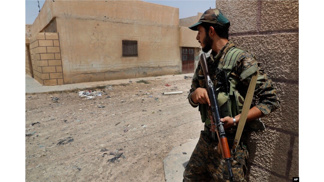 FILE - A U.S.-backed Syrian Democratic Forces fighter takes cover behind a wall on a street where they fight against Islamic State militants, on the front line on the western side of Raqqa, Syria, July 17, 2017.