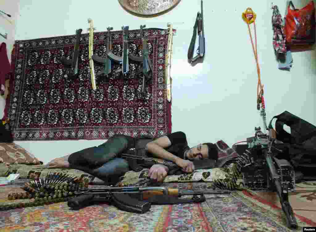 A rebel fighter rests next to weapons in a house in Hamidiyeh, Homs, Syria, July 1, 2012.