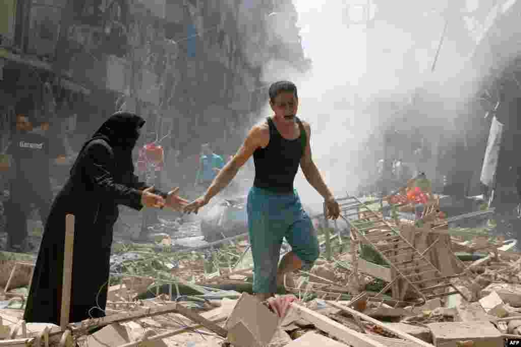 People walk amid the rubble of destroyed buildings following a reported air strike on the rebel-held neighborhood of al-Kalasa in the northern Syrian city of Aleppo.