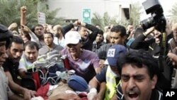 A Bahraini anti-government demonstrator lies injured on a stretcher as Bahraini anti-government demonstrators take him to hospital in Manama, Bahrain, early Thursday morning, Feb. 17, 2011