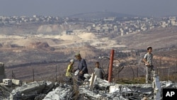 Jewish settler boys stand atop ruins of razed buildings in the unauthorized Jewish hilltop outpost of Migron, near the West Bank city of Ramallah, September 5, 2011.