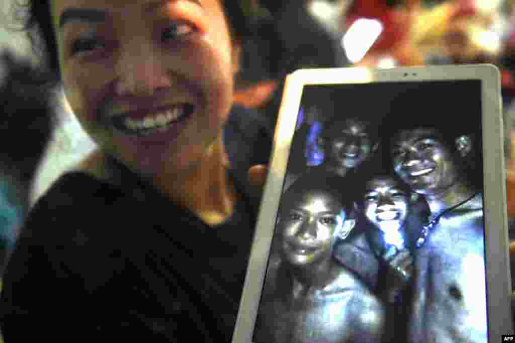 A happy family member shows the latest picture of the missing boys taken by rescue divers inside Tham Luang cave when all members of children&#39;s football team and their coach were found alive at Khun Nam Nang Non Forest Park in the Mae Sai district of Chiang Rai province, northern Thailand. Twelve boys and their football coach trapped in a flooded cave for nine days were &quot;found safe.&quot;