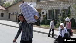 Syrian refugees walk with their belongings on the Lebanese-Syrian border, in al-Masnaa, July 20, 2012