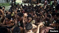 Migrants who were found at sea on a boat sit near Kanyin Chaung jetty after landing outside Maungdaw township, northern Rakhine state, Myanma,r June 3, 2015. 