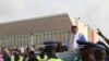 Former President Abdoulaye Wade is escorted out of Dakar international airport, Dakar, Senegal, July 10, 2017. (S. Christensen/VOA)