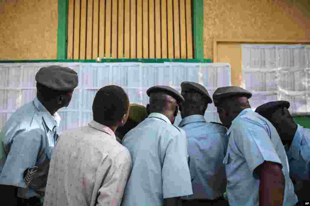 Members of the Sudanese security forces look for their names on a voters list outside a polling station where they are due to vote, on the first day of Sudan's presidential and legislative elections, in Khartoum, April 13, 2015.