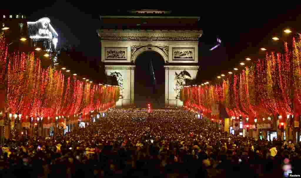 People attend New Year celebrations on the Champs-Elysees avenue as the traditional light show and fireworks have been canceled due to the spread of the COVID-19 in Paris, France, Dec. 31, 2021.