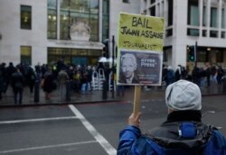 Pendukung Julian Assange memegang plakat di luar Pengadilan Westminster di London, Rabu, 6 Januari 2021.