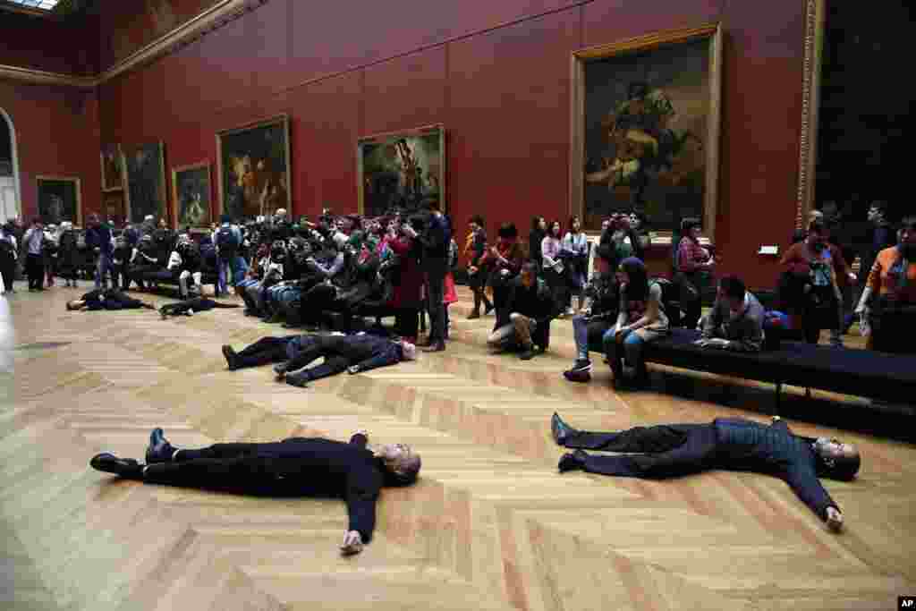 Activists lie on the floor inside the Louvre museum, as they stage a protest trying to call attention to migration driven by climate change, and notably to criticize activities of French oil giant Total, a prominent sponsor of Louvre activities, in Paris, France.