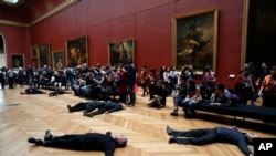 Activists lie on the floor inside the Louvre museum, as they stage a protest trying to call attention to migration driven by climate change, and notably to criticize activities of French oil giant Total, a prominent sponsor of Louvre activities, in Paris, March 12, 2018.