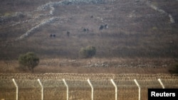 Rebel fighters are seen in Syria near the border fence with the Israeli-occupied Golan Heights, Sept. 2, 2014. 