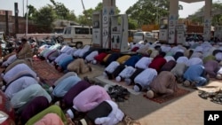 FILE - Indian Muslims offer Eid al-Fitr prayers in the shade of a petrol filling station as they join others offering prayers in an open area in Hyderabad, India, June 16, 2018. 