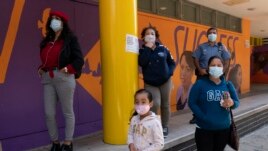 People listen as members of the NY Phil Bandwagon perform outside the Casita Maria Center For Arts & Education in the Hunts Point neighborhood of the Bronx borough of New York, Friday, Oct. 2, 2020. (AP Photo/Mary Altaffer)