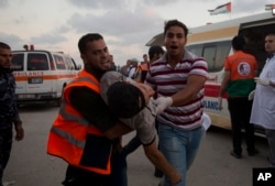 Palestinian medics carry a wounded man into a field clinic after being shot by Israeli troops during a protest at the Gaza Strip's border with Israel, July 20, 2018. Israel carried out airstrikes and deployed tanks at militant sites in Gaza killing four Palestinians Friday after gunmen shot at soldiers near the border, officials said.