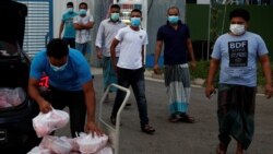 Para pekerja migran yang tinggal di asrama milik pabrik mengambil makanan yang didonasikan oleh sejumlah badan amal untuk Idul Fitri di tengah wabah virus corona di Singapura, 24 Mei 2020. (Foto: Reuters)