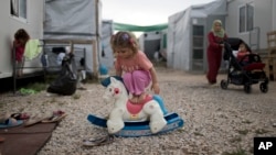 A Syrian child plays with a plastic toy horse at the refugee camp of Ritsona about 86 kilometers (53 miles) north of Athens.