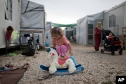 A Syrian child plays with a plastic toy horse at the refugee camp of Ritsona about 86 kilometers (53 miles) north of Athens.