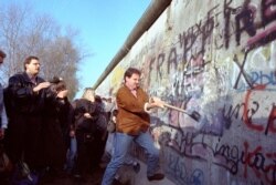 An unidentified West Berliner swings a sledgehammer, trying to destroy the Berlin Wall near Potsdamer Platz, on November 12, 1989, where a new passage was opened nearby. (AP Photo/John Gaps III)