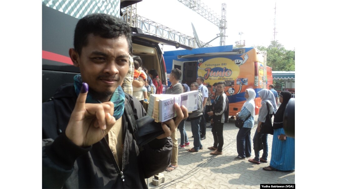 Seorang warga menunjukkan jari bertinta mengantisipasi calo jasa penukaran uang baru di lokasi penukaran uang perbankan di Solo, Solo, 5 Juni 2018. (Foto: VOA/Yudha Satriawan)
