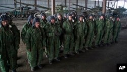 FILE - Russia-backed rebels are seen lined up in front of tanks near Novoazovsk, eastern Ukraine, Oct. 21, 2015. According to U.N. figures, more than 9,000 people have been killed and 21,000 injured in the conflict in eastern Ukraine since it began nearly two years ago.