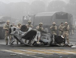 Pasukan keamanan terlihat berjaga di alun-alun utama tempat ratusan orang memprotes pemerintah, setelah keputusan pihak berwenang untuk menaikkan batas harga bahan bakar gas cair, di Almaty, Kazakhstan, 6 Januari 2022. (REUTERS/Mariya Gordeyeva)